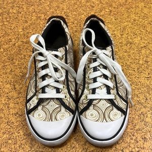 Coach canvas sneakers with brass and leather accents.